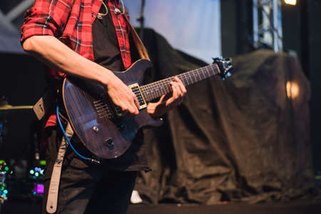Electric guitar in the hands of a rocker. A man plays the guitar at a rock concert.
