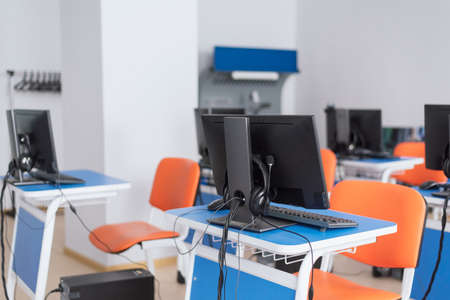 empty computer classroom with bright blue desks and orange chairs. teaching children programming....