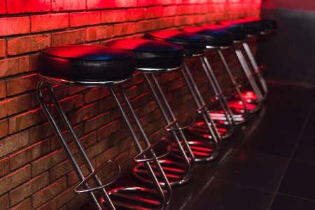 bar stools at the counter in neon light. leather chairs at the barの写真素材