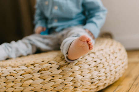 children's leg in gray pants on a beige pouf. Cute little leg