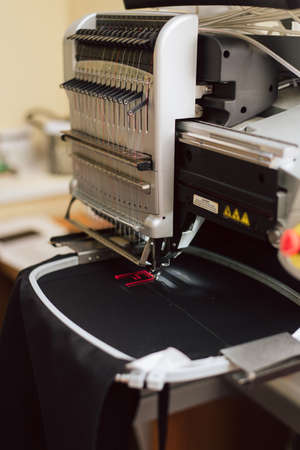 embroidering text on a sewing machine on an industrial scale. machine embroiders the letter f on the fabric. sewing manufacture at the factory.の写真素材