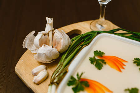 aspic, decorated with carrots, parsley on a wooden background. Russian-national food with moonshine, vodka, garlic, green onions and bread with mustard.の写真素材
