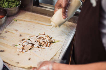 Cooking fajitos in the cafe. Cooking shawarma in pita in the kitchen. Wrap chicken, carrots,...
