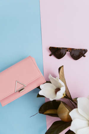 top view and female fashion concept, minimalism. Glasses and pink bag on a pastel pink and blue...