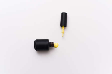 yellow gel nail polish in a black bottle on a white background. Manicure concept for blogs and...