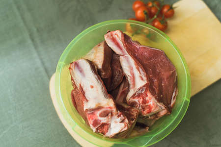 raw meatb and tomatoes in plastic cups. Preparation in cooking pilau in the kitchen.