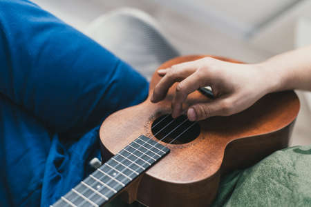 ukulele game. a man playing a little guitar. the performer writes the music on the ukulele at home.