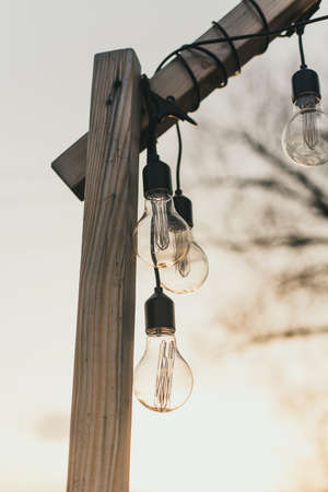 light bulbs in the street in daylight. A garland of light bulbs on a wooden pedestal in the afternoon in the sun outdoor.の写真素材