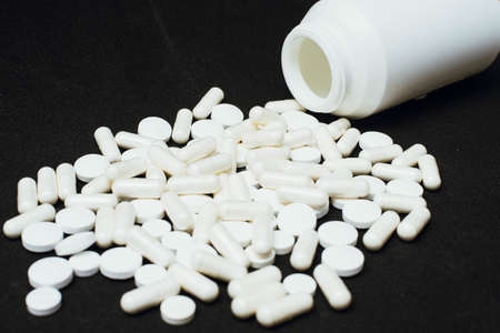 White pills on a black background. The concept of health, pharmaceuticals and treatment.