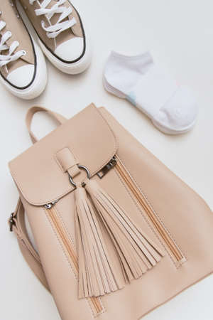 Beige sneakers, backpack and pink cap on pastel light background. Place for text, copyspace, flat...