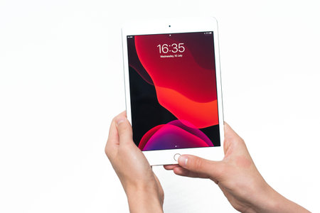 Samara, Russia -07, 29, 2019: Teenage boy holding iPad Air with beta Ipados 13 on white background. The main menu of the iPad in the hands of a young man.のeditorial素材