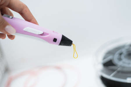 3d pen in the hands of a girl. Drawing with the 3D pen. Coils with plastic for locking a 3D printer.の写真素材