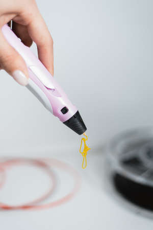 3d pen in the hands of a girl. Drawing with the 3D pen. Coils with plastic for locking a 3D printer.の写真素材