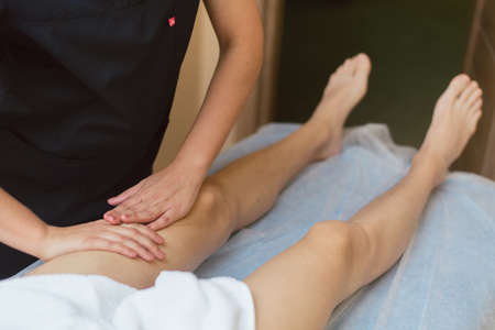 Masseur doing massage the knee to the young man. The doctor massages the leg for treatment.の写真素材