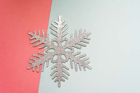 Christmas glitter snowflake lies on a pastel pink and blue background. New Year card, copyspace.の写真素材