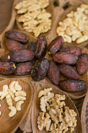 dried dates and walnuts on a wooden dish. vertical photo of oriental sweets