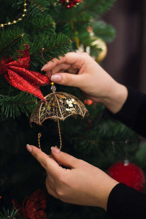 A man hangs a christmas toy on a New Year tree with a garland.の写真素材