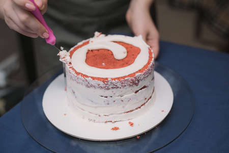 The confectioner levels the cream on the cake. The cook creates a cake, collects it and covers it...