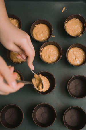 The baker creates cupcakes in molds. The baker creates carrot muffins.の写真素材