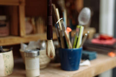 Art brushes in a potter's workshop. An old brush hangs from a shelf.
