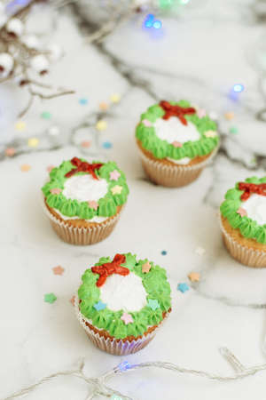 New Year's sweets on a marble table. Christmas cupcakes decorated with mastic and cream.の写真素材