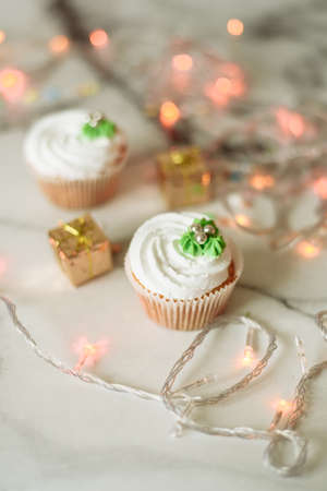 New Year's sweets on a marble table. Christmas cupcakes decorated with mastic and cream.の写真素材