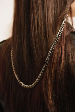 Heavy chain at the points of metal on the dark hair of a young girl. Metal stylish eyeglass chain.