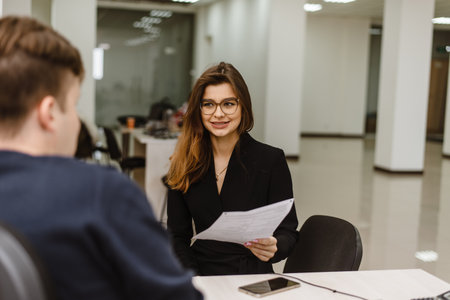 Samara, Russia - 02.11.2019: Hiring an attractive girl. A girl in glasses and a suit sits in the office at the table in front of a mans boss and is interviewed for a job.のeditorial素材