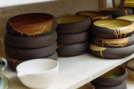 Interesting handmade ceramic plates on the shelf of the Potter's workshop.の写真素材