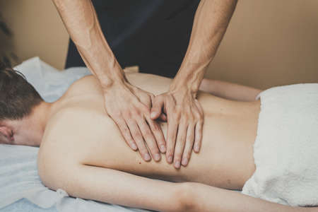 A man is given a back massage. Relaxation on the massage table. Beautiful tinted.の写真素材