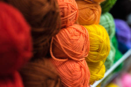 Shelf with a lot of color yarn for diy knitting. Selection of colorful yarn wool on shopfront. Knitting background. Knitting balls of wool, crochet hooks pattern. Skeins of wool of all colors of the rainbow.の写真素材
