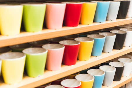 Colored glasses on the shelves in the store. ups of all colors of the rainbow on the counter of the store.の写真素材