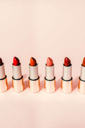 Multi-colored lipsticks stand in a row on a pink background. The concept of different, collections and beauty. Red, pink and burgundy lipsticks.の写真素材