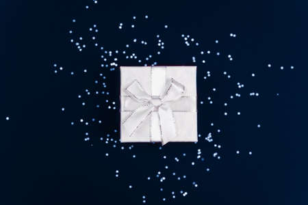 Classic blue, toned image. White gift on a blue background with confetti. Trend of the season 2020. Classic blue is the New color of the year.の写真素材