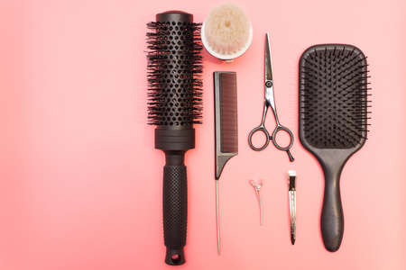 Flat lay composition with hairdresser set on pink background. Barber set with tools and equipment: scissors, combs and hairclips with copy space for text in left. Hairdresser and beauty salon service.の写真素材