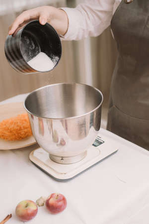 Preparation dough cooking, pouring the sugar in the the metal bowl. Pouring sugar into saucepan. Cooking dough. The cook pours sugar into the bowl for mixing.の写真素材