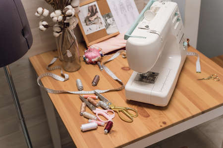 The workplace of a seamstress. Sewing machine on the table, thread, scissors and mannequin.の写真素材