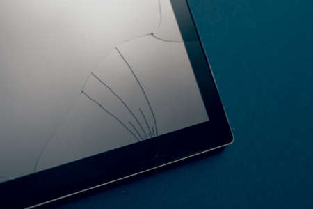Modern tablet on a classic blue background with cracks. Broken screen of a tablet, smartphone or...