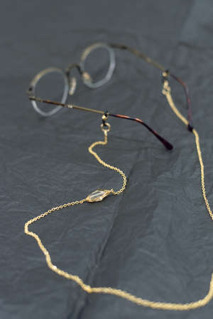 stylish gold chain with a transparent gem on the glasses. trend on chains for points. Vintage glasses black, wrinkled parchment paper.の写真素材