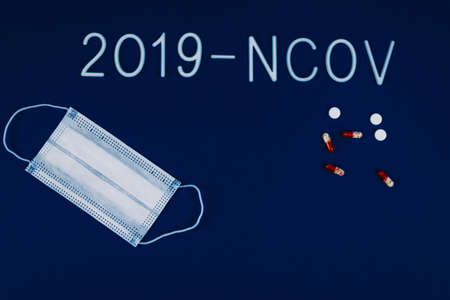the word 2019-ncov laid with white letters on classic blue background with dramatic light. Novel coronavirus disease named 2019-nCoV . Pills and breathing mask as a concept of coronavirus.の写真素材