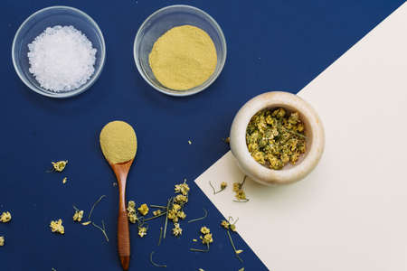 This face pack removes dead skin. Collagen powder or yellow clay on classic blue and beige background with wooden spoon. Flat lay style. Home skin care. Modern apothecaryの写真素材