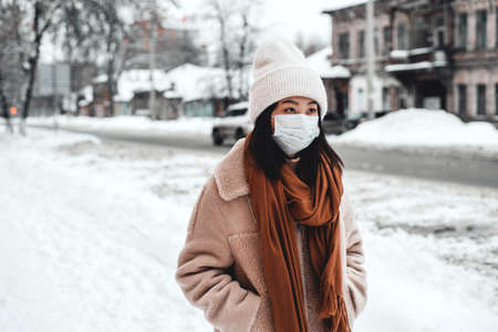 A woman on the street in winter protects the respiratory tract from the epidemic of coronavirus. Protection against urban smog and dust.の写真素材