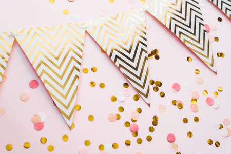 Template for the holidays. Paper garland of flags on a pink background with confetti.