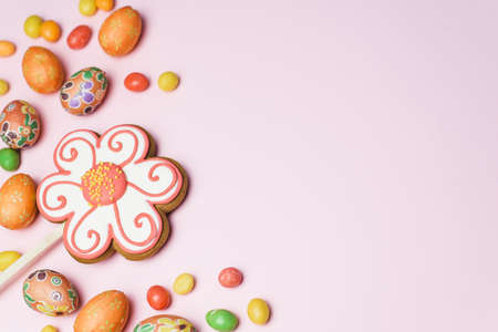 Easter gingerbread, sweet colored candies and small, decorative eggs on a pink background. Easter...