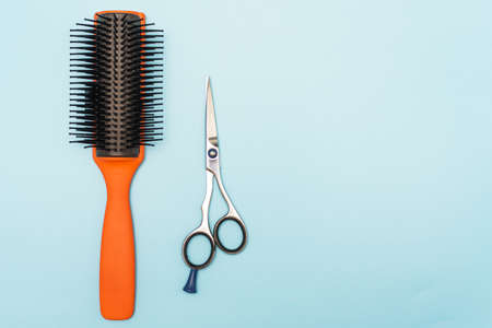 Professional black comb and scissors. Hairdresser tools on a blue pastel background.