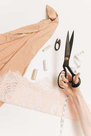 Hand of seamstress on the background of fabrics and scissors on the table. Scissors, fabric, a seam...