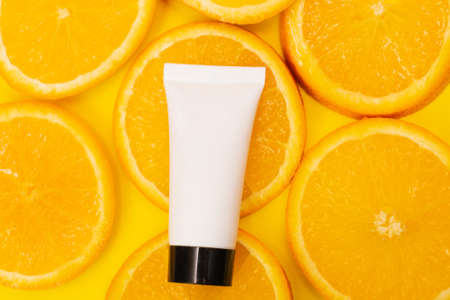 Natural vitamin c skincare product with fresh juicy orange fruit slices on yellow background....