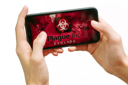 Samara Russia - 04.05.2020: A young man plays in Plague Inc Evolved on iPhone 11. Isolated hands of...