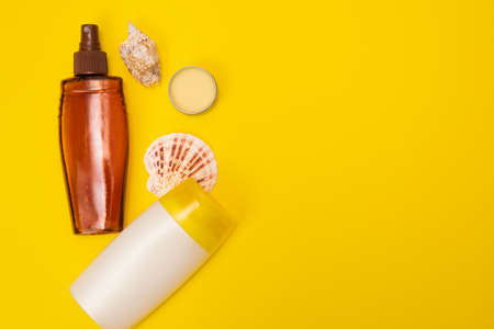 A suncream with shells are on the yellow background. Sun protection products are on the yellow...