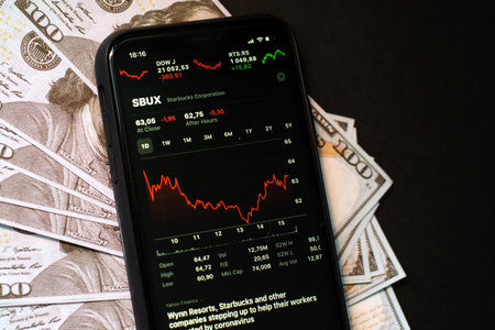 Samara Russia - 04.05.2020: Starbucks Corporation on the screen of iPhone 11 against the backdrop of hundred-dollar bills. The fall and growth of stocks, the concept of a brokerage account, dividends and profits.のeditorial素材